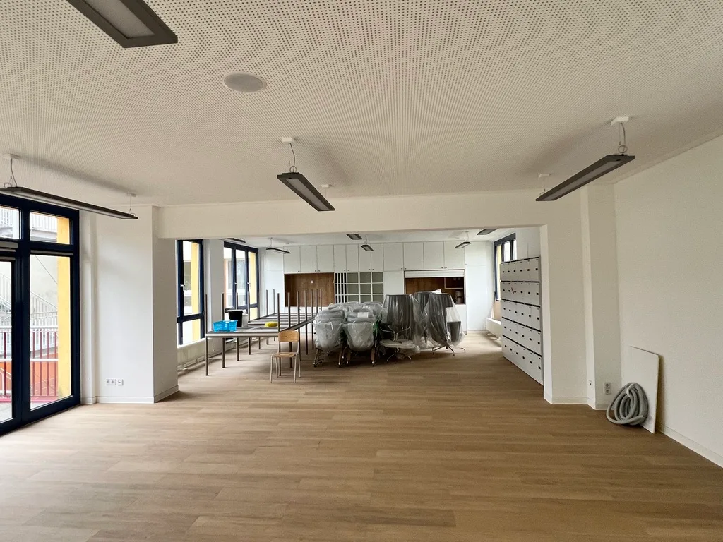 Fertiggestellter Anbau eines Schulgebäudes mit weißen Wandflächen und Boden in Holzoptik